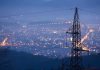 Night view of a city skyline with power lines in the foreground
