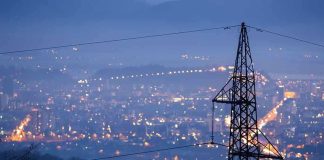 Night view of a city skyline with power lines in the foreground