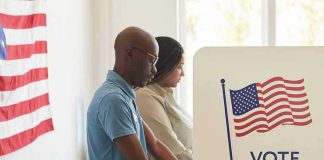 People voting at polling booths with American flag.