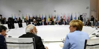 Trump Caught SLEEPING at Summit – Is He Struggling? People seated around a large round table, flags behind.