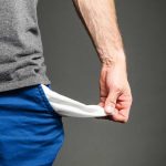 American Dream Crushed by Soaring Costs Person pulling out empty pocket from shorts.