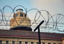 Luxury Meals Smuggled In — Prison Scandal Unfolds Barbed wire in front of a prison tower.