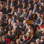 GOP District IMPLODES – Congressional Seat on the Line! Audience of officials sitting and reading documents in auditorium.