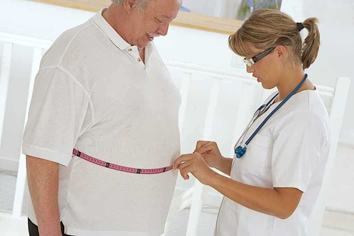 shutterstock_165451763.jpg A healthcare professional measuring a patients waist with a tape measure