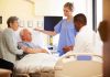 A nurse and a doctor discussing with a patient and his family in a hospital room