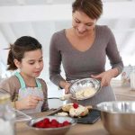 A mother and daughter baking together in a bright kitchen