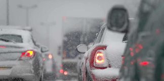 Cars stuck in traffic during a snowstorm with snow covering the vehicles