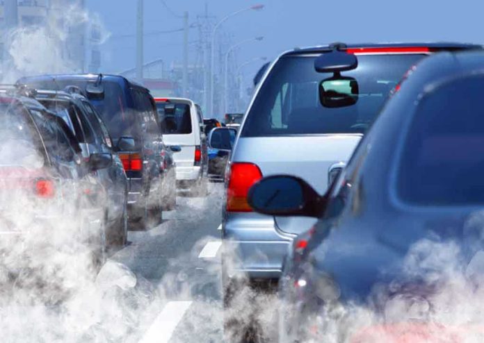 Traffic jam with cars emitting exhaust fumes on a city road