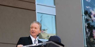 Maher STUNNED When Woke Liberal Breaks Ranks A man in formal attire speaking at a podium during a Hollywood Walk of Fame ceremony