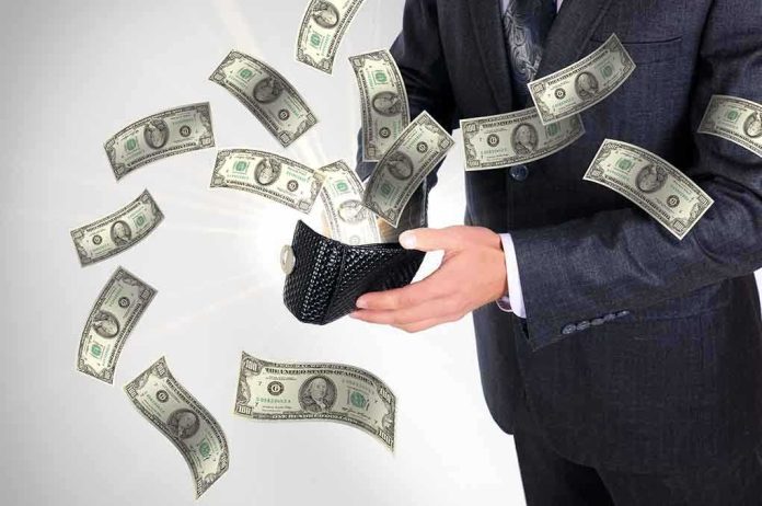 A businessman holding a wallet with money flying out