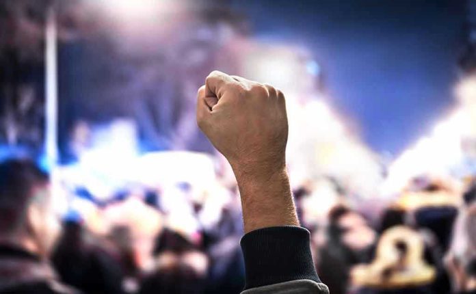 1227767950 Raised fist in a crowd at night.