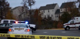 Sheriff line tape blocking scene with police and ambulance.