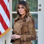 SHOCKING Violation Triggers Melania’s Nuclear Response Woman in brown coat beside American flag.