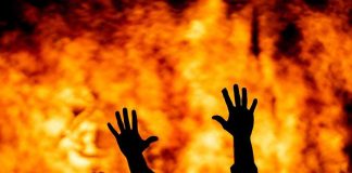 Outrage Erupts: Leaders Blamed for Fire Chaos Silhouetted hands raised against a fiery background.