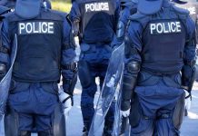 Police officers in riot gear with shields.