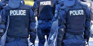 Police officers in riot gear with shields.