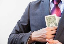 Massive Medicare Fraud — $14.5M Scheme Exposed! Person in suit putting dollars in jacket pocket.