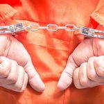 Hands in handcuffs wearing an orange jumpsuit