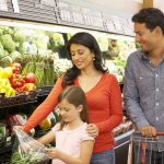 A family shopping for fresh vegetables in a grocery store