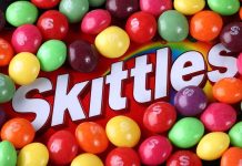 A colorful assortment of Skittles candies surrounding the Skittles packaging