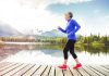 Senior woman jogging along a lakeside with mountains in the background