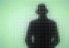 Police Weaponize YOUR Own Face Silhouette behind frosted, textured glass in green light.