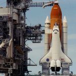 NASA Clears Final Hurdle — Moon Launch IMMINENT Space shuttle on launch pad with support structure.