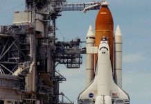 NASA Clears Final Hurdle — Moon Launch IMMINENT Space shuttle on launch pad with support structure.