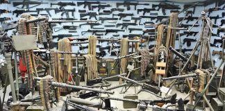 Room filled with various firearms and ammunition belts.