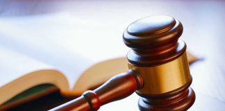 Gavel resting on sounding block beside open book.