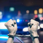 Trained Attackers Beat Student to Death Hands in handcuffs in front of police cars.