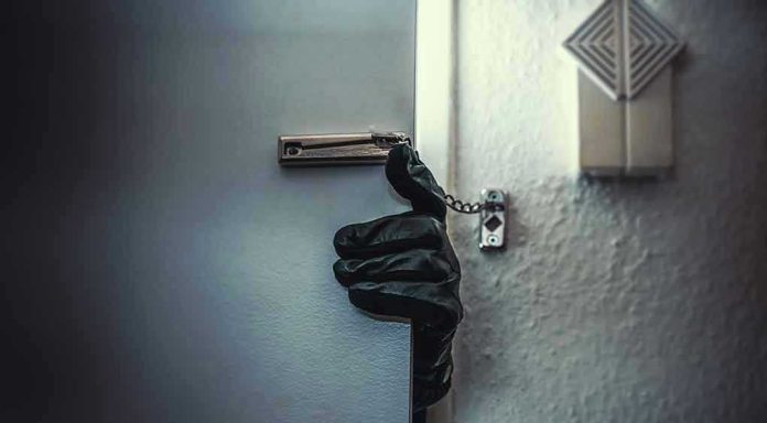 Gloved hand opening door with security chain.