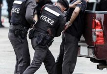 Police officers arresting a handcuffed person.
