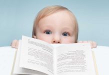 A curious baby peeking over an open book