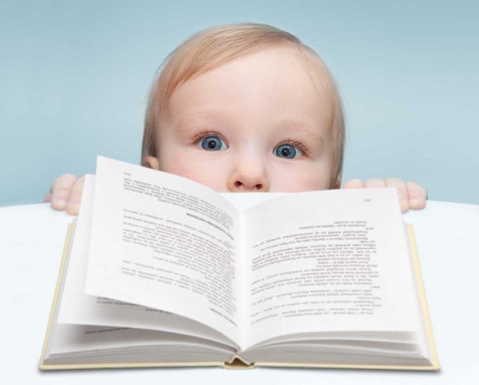 A curious baby peeking over an open book