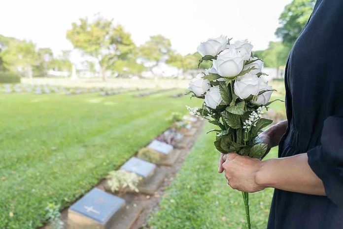 1569972004 Person holding white roses at a cemetery.
