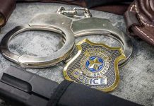 Police Badge Predator Exposed Handcuffs, officer badge, and firearm on textured surface.