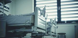 Empty hospital beds by a window.