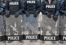 Police officers in riot gear holding shields.