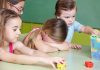 Children at a table with building blocks, one child appears upset