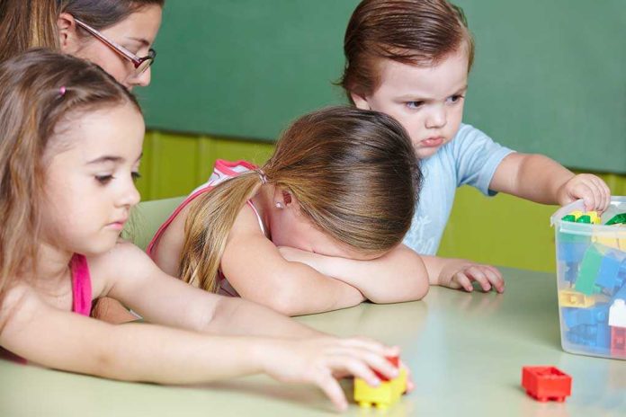 Children at a table with building blocks, one child appears upset