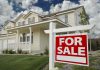 A suburban house with a For Sale sign in the front yard