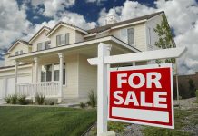 A suburban house with a For Sale sign in the front yard