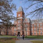 Historic university building with students walking in front during autumn