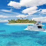 A luxury yacht cruising in clear blue waters near a tropical island