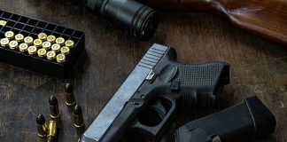 Dad SHOOTS Predator—Arrested Anyway Handgun with ammunition, magazine, and rifle on wooden table.