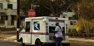 USPS HALTS Pension Payments — Mail Delivery Threatened USPS mail carrier at truck near stop sign.