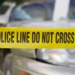 Yellow police tape in front of a car.