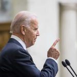 Democrats ERASE Biden From White House History Man in suit pointing while speaking at podium.