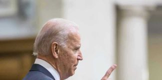 Man in suit pointing while speaking at podium.